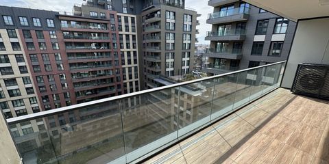 View from an apartment balcony across to neighbouring blocks, rows of multi-storey residential buildings behind a glass balustrade
