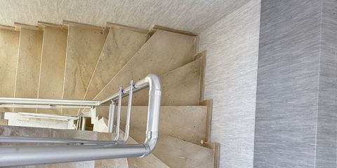 A marble winder staircase in an unfinished building, with metal handrails fitted along the wall