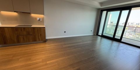 Empty apartment living room with a fitted kitchen and wide windows