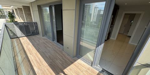 A wide balcony with wood-effect tiles and sliding doors, the marble-floored interior of the apartment visible through them