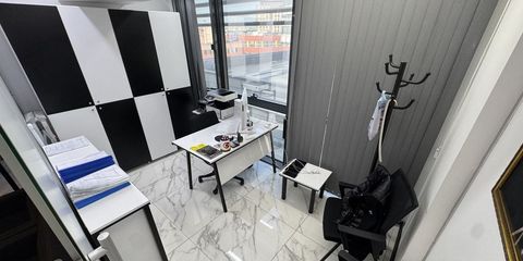 Küçük bir ofis odası; çalışma masasında yazıcı, yanda dosya klasörleri ve pencereden şehir görünümü