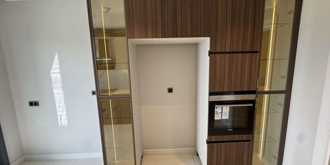 Bir dairenin mutfağında koyu ahşap boy dolaplar, ankastre fırın ve buzdolabı için boş bırakılmış niş